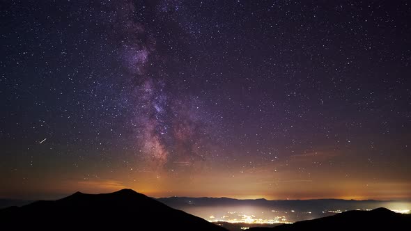 The Core of the Milkyway in the Night Skythe Silhouette of the Hills and Glowing City in the Valley