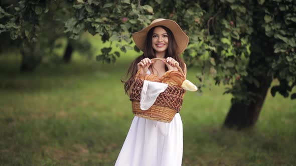 Young Beautiful Woman with White Teeth, a Beautiful Smile in a Straw Hat Walks To the Green Park in