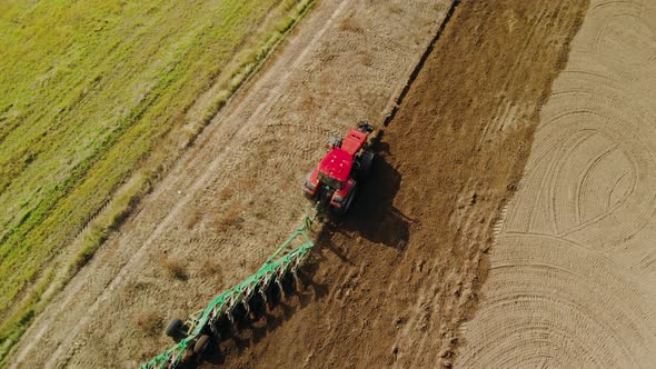 Tractor with Multi-plow on Farmland in Sunny Weather in Spring and Autumn. Plowing the Soil for alt