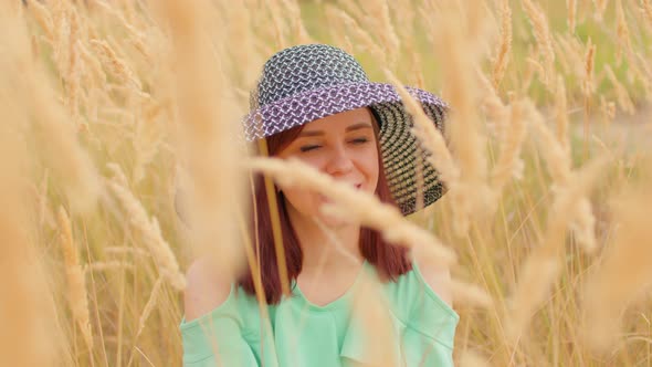 Young Woman in Dress and Hat Sitting in Wheat Field alt