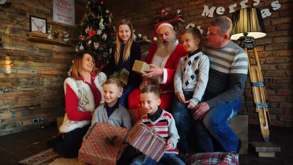 Santa Claus Gives New Year Gifts To Big Family in Decorated Room for Christmas with Tree