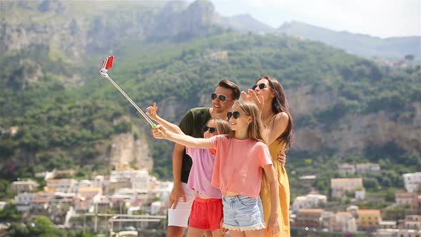 Parents and Kids Taking Selfie Photo Background Positano Town in Itali on Amalfi Coast alt