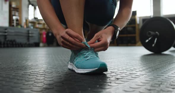 Front view low section of an athletic Caucasian woman tying her shoelaces alt