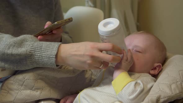 Mother Holds Phone Feeds Baby alt