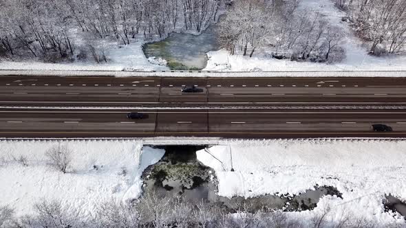 Winter Time Aerial Top Down View of a Snowy Road Surrounded Pine Tree Forest alt