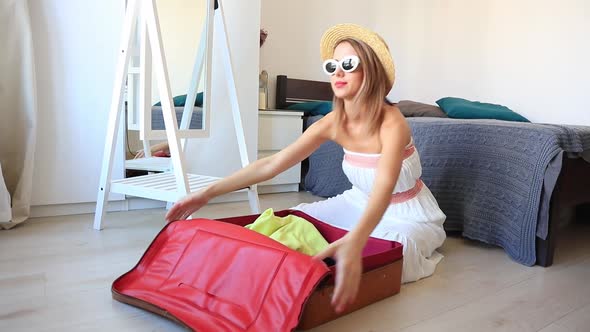 Young girl preparing for vacation. Pack up clothes in suitcase at home. alt