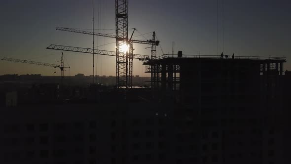 Construction Site at Sunset. Silhouette of a Construction Crane Near the Building