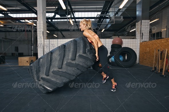 Fit female athlete flipping a huge tire - Stock Photo - Images