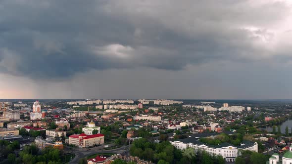 Flying high above the city. Beautiful dark blue clouds. Top view on houses, roads, cars.