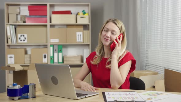Warehouse Worker is Working in an Office Room Against Background of Boxes alt