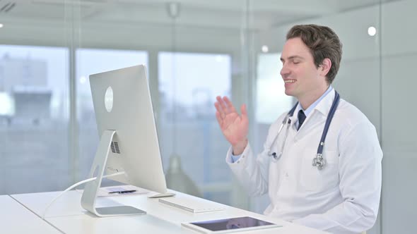 Cheerful Young Doctor Doing Video Chat on Desk Top  alt