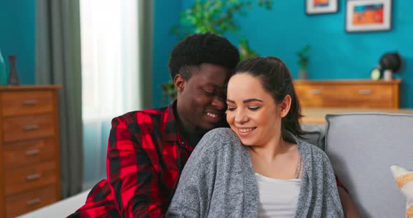 Happy Couple Bonding to Each Other and Smiling While Sitting on Couch alt