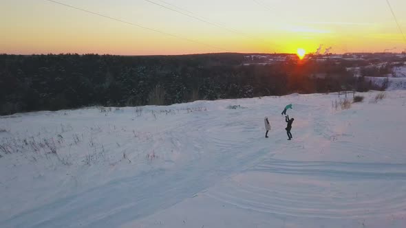 happy family relaxes on snowy field against orange sky alt