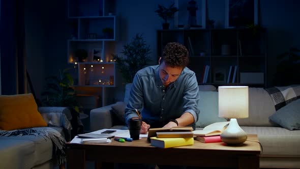 Young Man Dancing While Sitting on a Couch While Studying at Night alt
