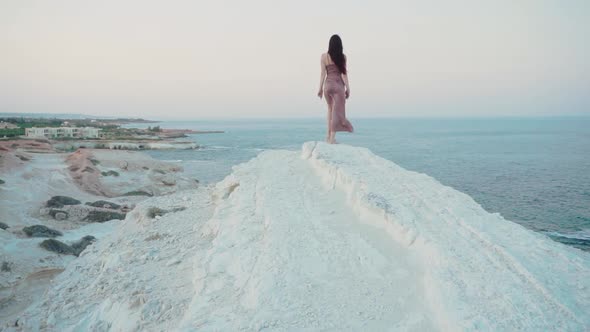 Woman Walks the Coastline on the Rocks