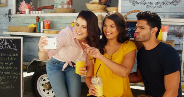 Friends taking selfie from mobile phone in food truck van alt