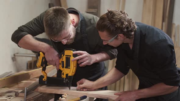 Carpenters with Drill Drilling Plank at Workshop alt