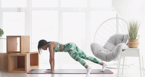 Young black woman making plank at home.