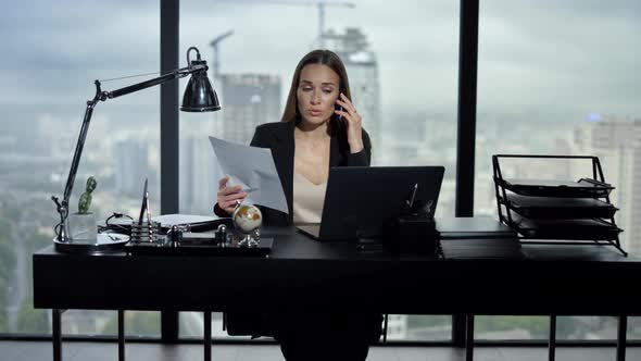 Businesswoman Talking on Smartphone in Office. Professional Looking at Documents alt