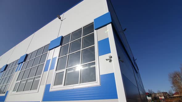 Stylish White and Blue Warehouse Building Against Clear Sky alt