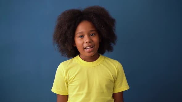 Cheerful happy small girl with dark skin smiling, talking something and looking at the camera. alt