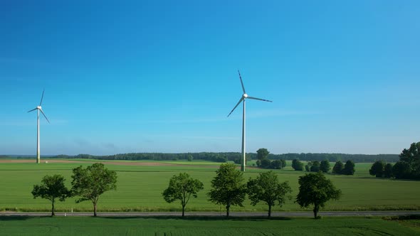 Wind Turbine Alternative Power Generator In The Field Against Clear Blue Sky. Aerial Wide Shot alt