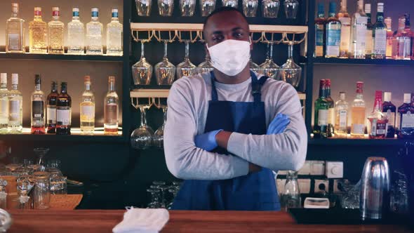 African Waiter in a Face Mask is Smiling Behind the Bar alt