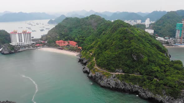 Aerial: flying over beautiful rocky coastline and promenade on the cliff at Cat Ba island, Vietnam alt