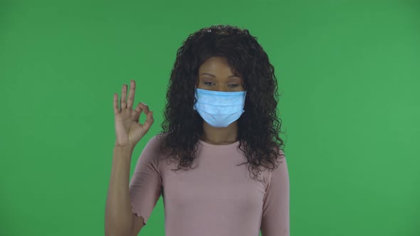 Portrait of Beautiful African American Young Woman in Medical Mask Is Looking Straight Sighs alt