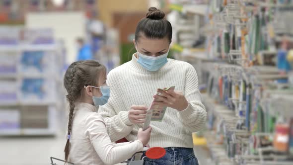 Mother and Child Wearing Protective Masks Choose Stationery at the Supermarket alt