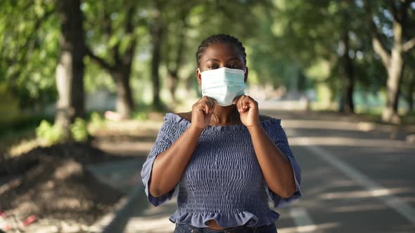 Young Plussize African American Woman in Covid19 Face Mask Looking at Camera with Serious Facial alt