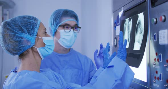 Diverse male and female surgeons wearing surgical caps and face masks discussing x ray alt