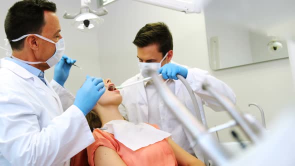 Dentists examining a male patient with tools alt