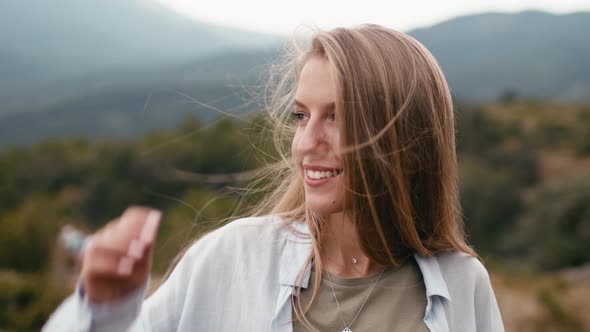Young Smiling Blonde Woman Standing in Mountains Portrait