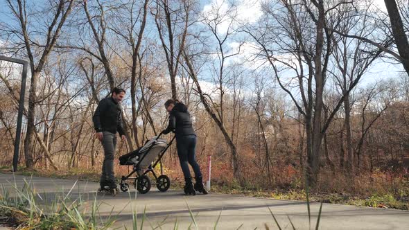 Sport Young Parents Roller Skate with Their Baby in a Stroller in a City Park. Autumn, Sunny Day alt