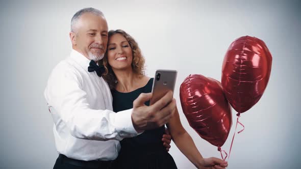 A Cheerful Husband and a Beautiful Joyful Wife with Balloons in the Form of Hearts in Their Hands