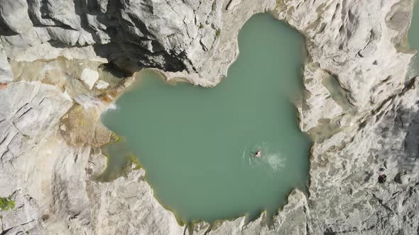 Tourists swim in the turquoise pool. aerial drone headshot of Albanian canyon "Syri i ciklopit". Alb alt