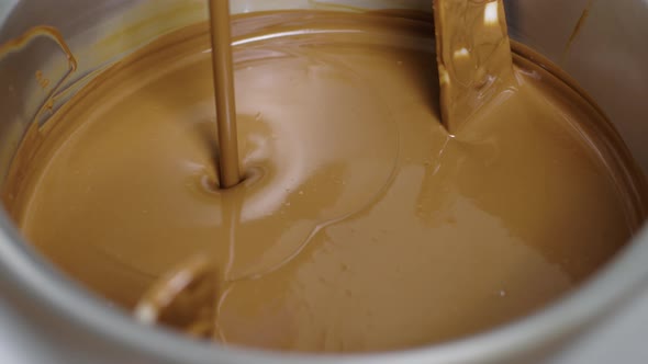 Jet of Melted Milk Chocolate Pours Into Smoll Mixer or Stirrer