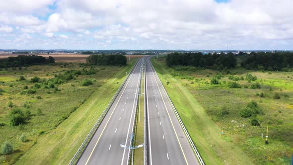 Empty Highway with Two Lanes and Streetlights Across Meadow