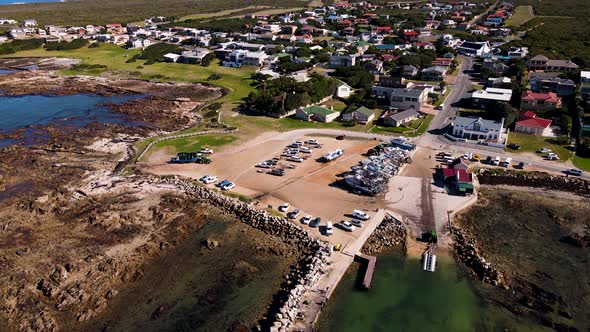 Aerial pullback reveals harbor where shark cage diving boats depart; Kleinbaai alt