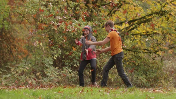 Two boys in Fall throwing leaves in slow motion