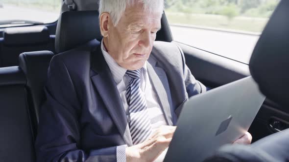 Senior Businessman with Laptop in Car alt