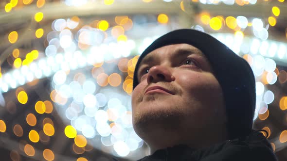 Smiling man admires festive city decorations alt