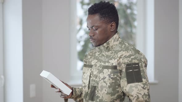 Side View Portrait of Upset Young African American Military Man Looking at Picture Thinking alt