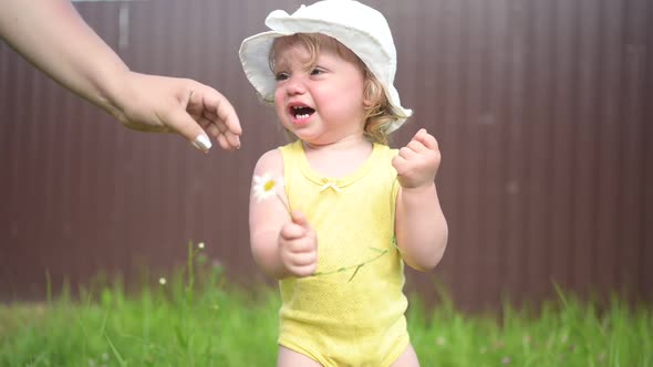 Little Funny Cute Blonde Girl Child Toddler Yellow Bodysuit White Hat Crying Playing with Daisy