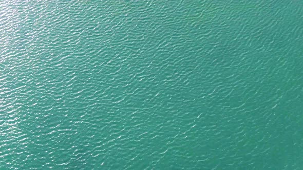 Turquoise wavy water with a white dock beach and mansions in Martha's Vineyard alt