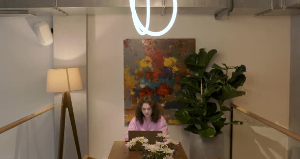 Beautiful millennial digital nomad working remotely on laptop computer. Inside coffee shop alt