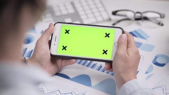 Businesswoman working and looking at green screen on smartphone