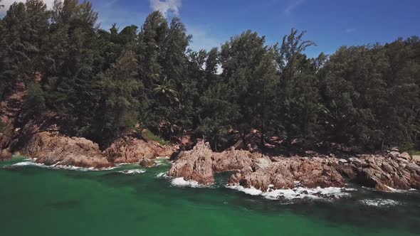 Panoramic aerial view of the tropical and rocky beach, waves crashing on rocks. Thailand.