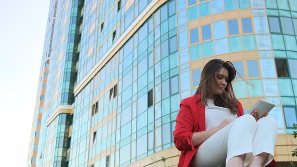 Business Woman Sitting on the Lawn, Against the Background alt